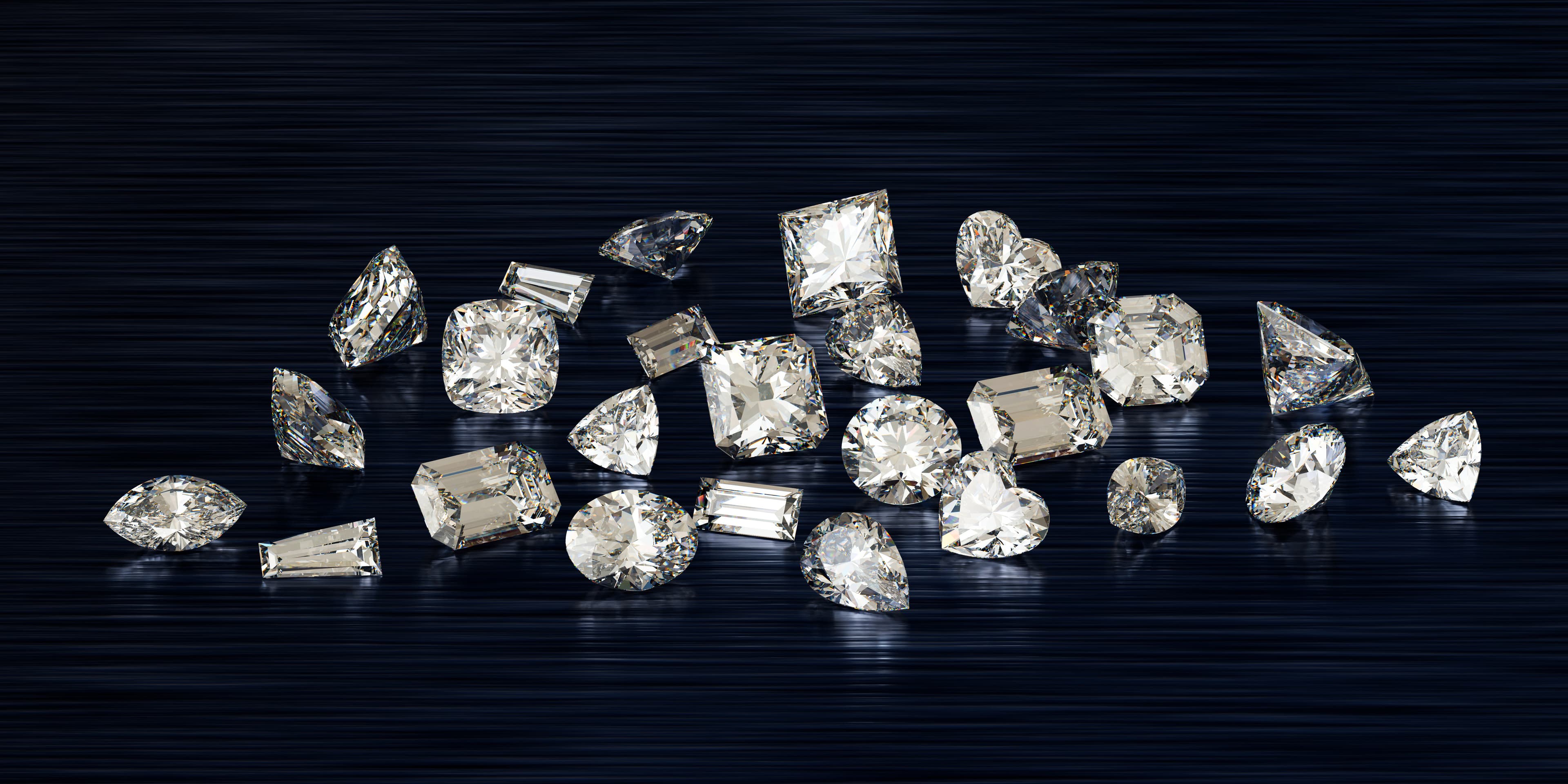 A row of six loose diamonds in round, oval, emerald, cushion, marquise and pear shapes on navy linen