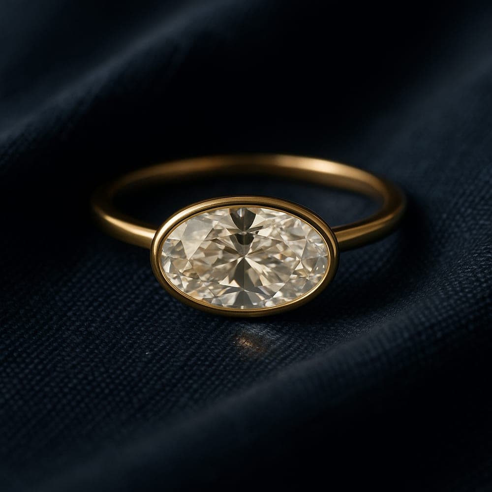 A moval diamond set east-west in a slim yellow gold setting