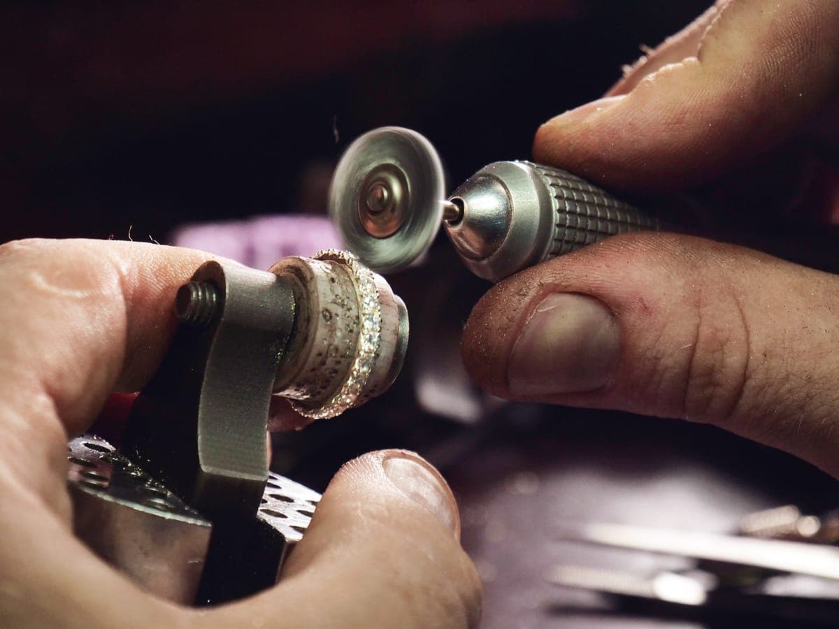 A jeweller polishing an engagement ring on a rotary polishing wheel at the workbench